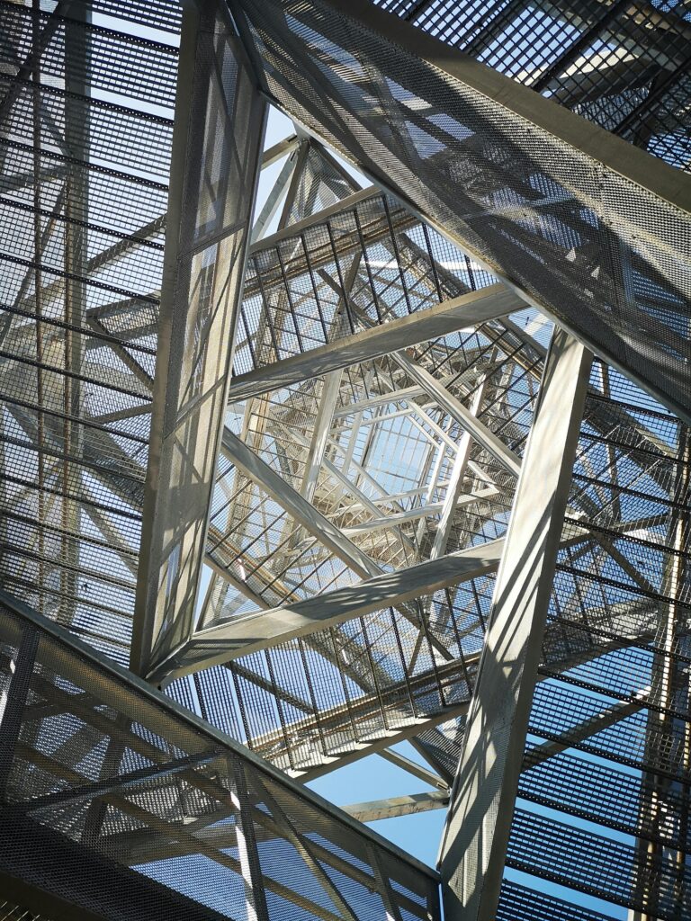 Captivating geometric perspective of a steel construction set against a clear sky, highlighting modern architectural design.